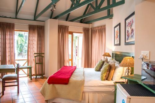 a bedroom with a bed with a red blanket on it at Hallack Manor in Port Elizabeth