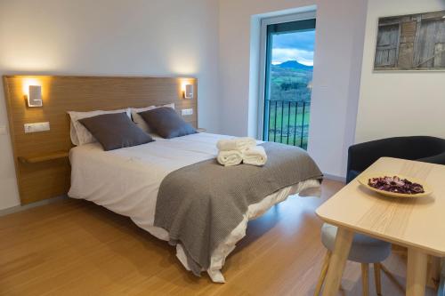 a bedroom with a bed and a table and a window at Mendialdea Amaiur Baztán in Maya del Baztán