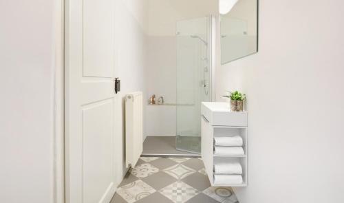 a white bathroom with a shower and a sink at Arcade Apartments in Bolzano