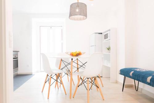 cocina blanca con sillas blancas y mesa en Casa do Calafate, en Nazaré