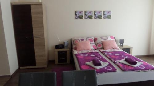 a bedroom with a bed with pink sheets and shoes at Rex Apartman in Hajdúszoboszló
