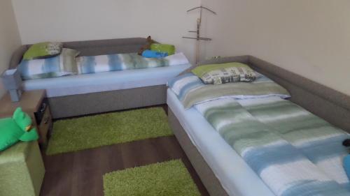 two beds in a room with green and blue at Rex Apartman in Hajdúszoboszló