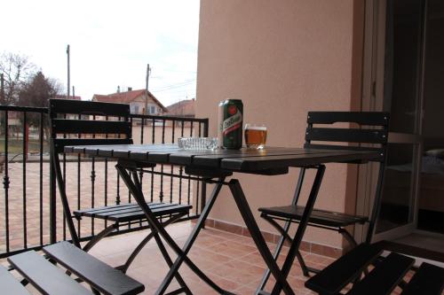 a table with a drink and two chairs on a balcony at Imola és Andrea Apartmanház 2 in Hajdúszoboszló