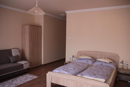 a bed in a room with a couch and a chair at Imola és Andrea Apartmanház 2 in Hajdúszoboszló