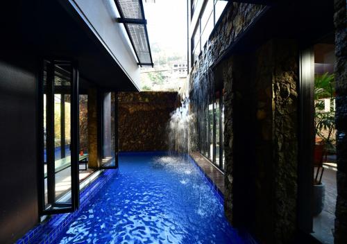 a swimming pool with a fountain in a building at Balinese onsen ryokan Hakone Airu in Hakone