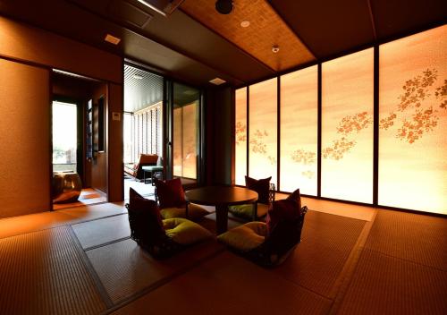 a living room with a table and chairs and windows at Balinese onsen ryokan Hakone Airu in Hakone