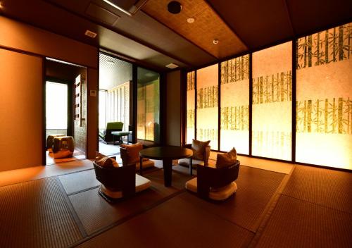 a living room with chairs and a table and windows at Balinese onsen ryokan Hakone Airu in Hakone