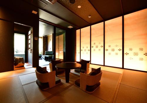 a living room with chairs and a table and windows at Balinese onsen ryokan Hakone Airu in Hakone