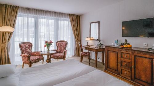 a hotel room with a bed and a table and chairs at Hotel Paryski Art & Business Zakopane - Basen Jacuzzi Sauna Małpi Gaj in Zakopane