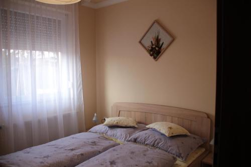 a bed with two pillows in a bedroom with a window at Imola és Andrea Apartmanház 2 in Hajdúszoboszló