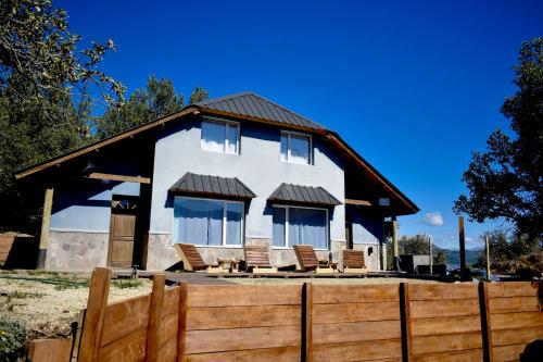 a house with chairs and a fence in front of it at Cabañas Agua Clara in Villa Pehuenia