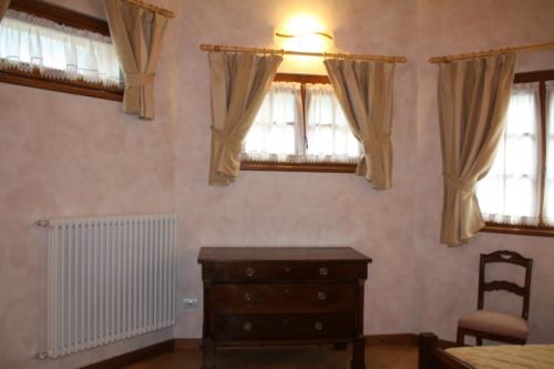 a bedroom with a dresser and two windows at Casa Vacanza La Rocca in Chiesa in Valmalenco