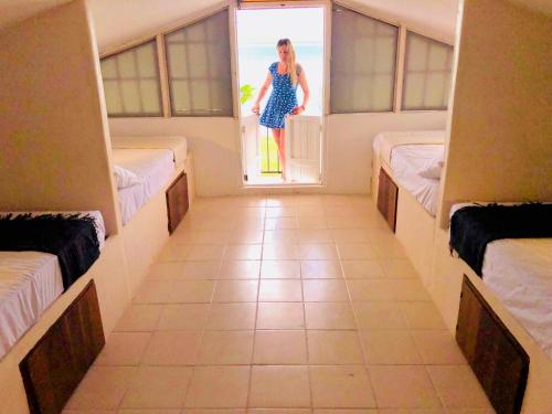 a woman standing outside a window in a room with beds at Hotel CasaBakal - A pie de Laguna - Bacalar in Bacalar