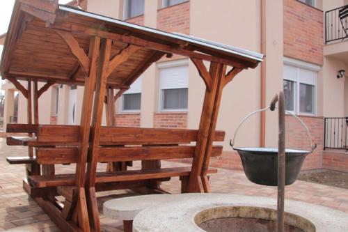 a wooden gazebo with a bucket in a courtyard at Imola és Andrea Apartmanház 2 in Hajdúszoboszló