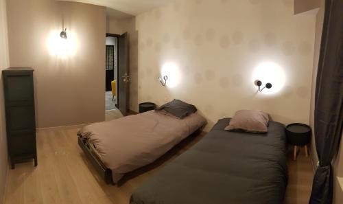 een slaapkamer met 2 bedden en 2 verlichting aan de muur bij le Gîte Ginkg'home in Saint-Max