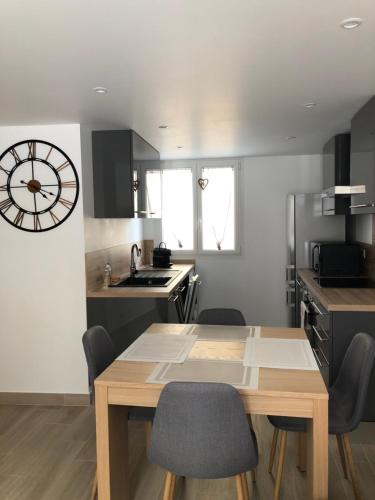 une cuisine avec une table en bois et une horloge au mur dans l'établissement Tout schuss, à Saint-Étienne-de-Tinée