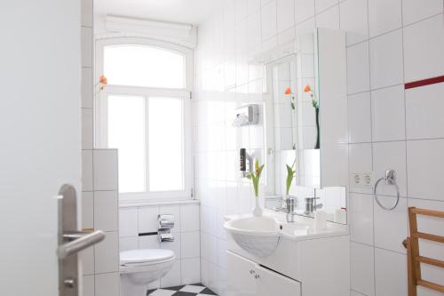 a white bathroom with a sink and a toilet at Pension Tokus in Nuremberg