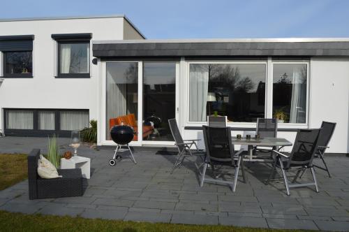 un patio con mesa y sillas frente a una casa en Ferienhaus Lemafri Duhnen, en Cuxhaven