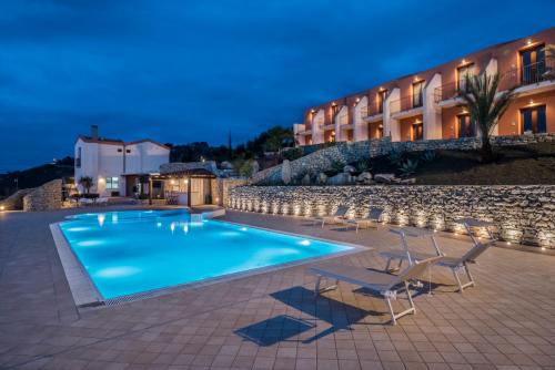 a swimming pool with chairs and a hotel at Hotel Parco Degli Aromi Resort & SPA in Valderice