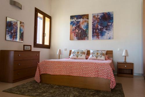 a bedroom with a bed and some paintings on the wall at Luxury apartment - Fort Chambray in Għajnsielem