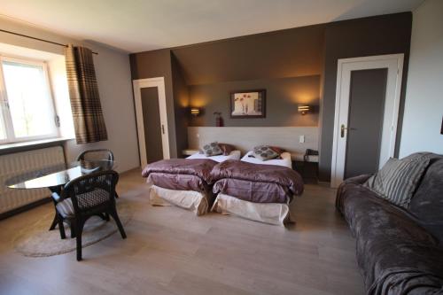 Zimmer mit 2 Betten, einem Tisch und einem Sofa in der Unterkunft Les Alisiers in Nadrin