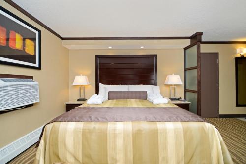 a large bedroom with a large bed with two lamps at Siding 16 Lodge in Wetaskiwin