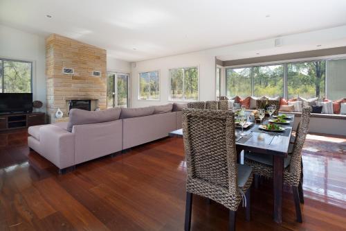 a living room with a couch and a table with chairs at Blue Cliff Retreat in Pokolbin