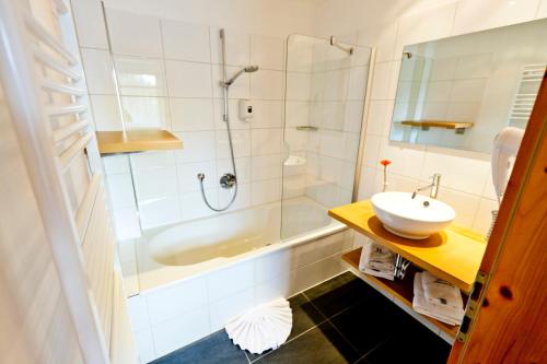 y baño con bañera, lavamanos y ducha. en Hotel Lärchenhof, en Katschberghöhe