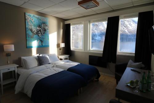 a bedroom with a large bed and two windows at Sogn Hotel in Vadheim