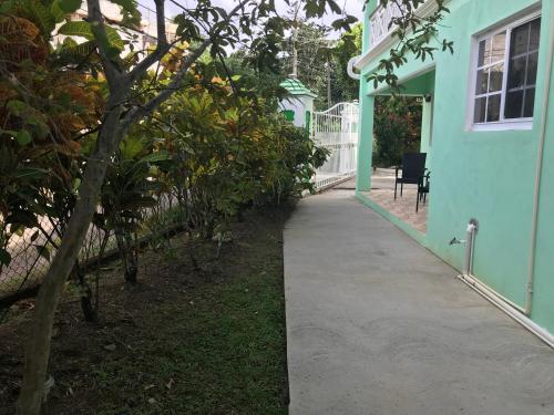 a walkway leading to a blue house with a tree at Marvey's Place in Castries