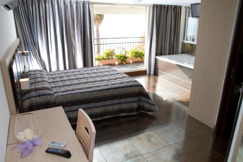 a bedroom with a bed and a table and a balcony at Hotel Ristorante Centosedici in Terracina