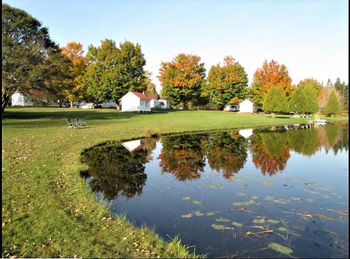 a pond in a field with a house and trees at Eden Village Motel and Cottages in Bar Harbor