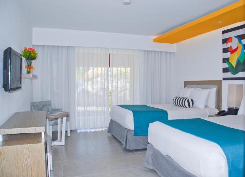 a hotel room with two beds and a window at Casa Marina Beach & Reef All Inclusive in Sosúa