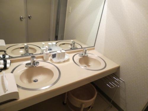 La salle de bains est pourvue de 3 lavabos et d'un grand miroir. dans l'établissement Azumino Hotaka View Hotel, à Azumino