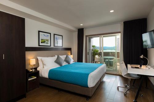 une chambre avec un lit, un bureau et une fenêtre dans l'établissement Quest Suva, à Suva