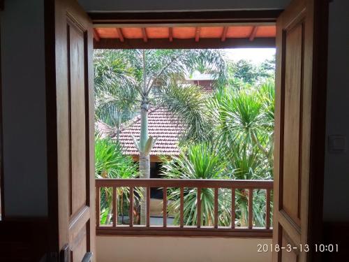 an open window with a view of a palm tree at Medewi Beach Inn in Pulukan