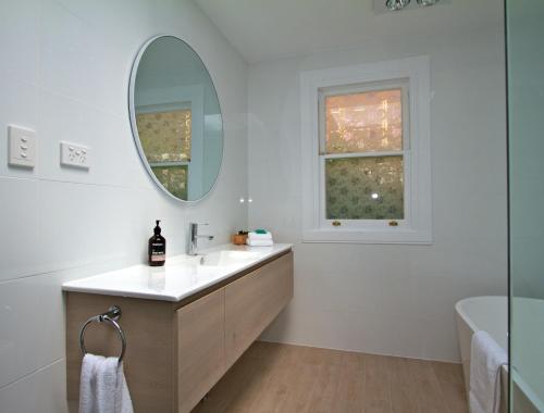 La salle de bains blanche est pourvue d'un lavabo et d'un miroir. dans l'établissement Strahan House, à Hobart