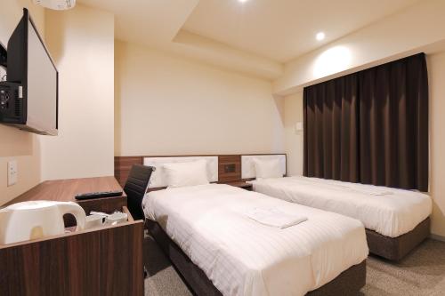 a hotel room with two beds and a sink at Welina Hotel Dotonbori in Osaka