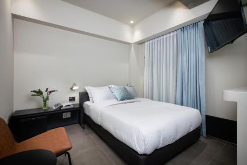 a bedroom with a bed and a desk and a window at Oia Hotel Dadaepo in Busan