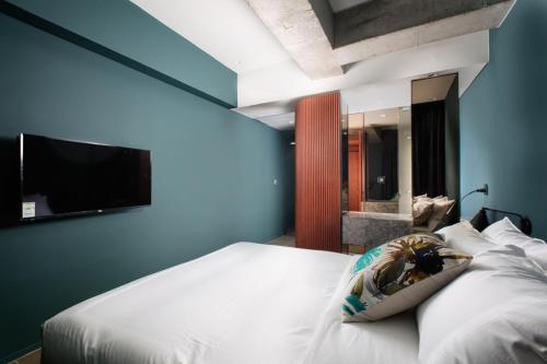 a bedroom with a bed with a tv on the wall at Oia Hotel Dadaepo in Busan