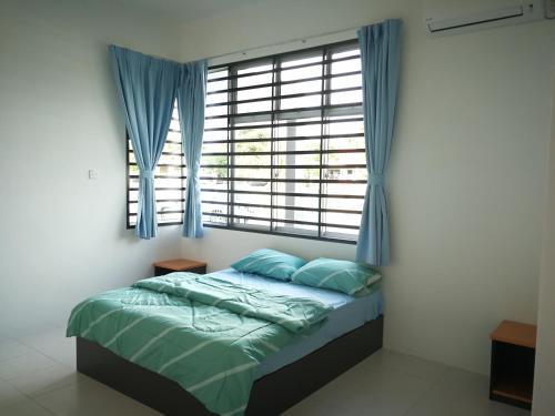 a bedroom with a bed and a window with blue curtains at Greenery Garden Concept Homestay in Kuantan