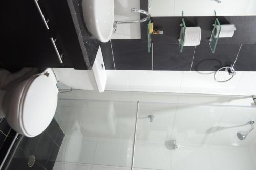Baño blanco con aseo y lavamanos en Hotel Quinta del Sol en Arauca