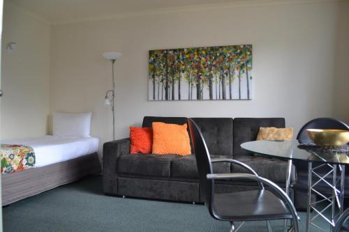 a room with a couch and a table and a bed at Colonial Lodge Motel in Taupo