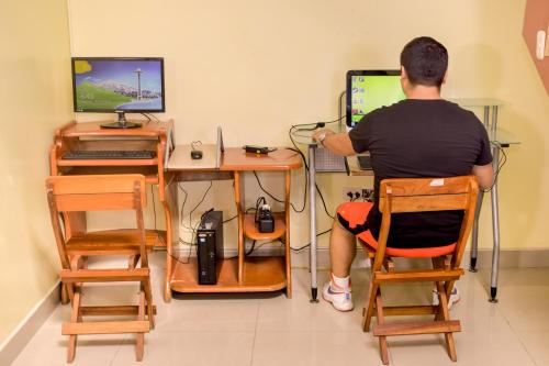 a man sitting in a chair in front of a computer at Hotel Ventura Isabel in Iquitos