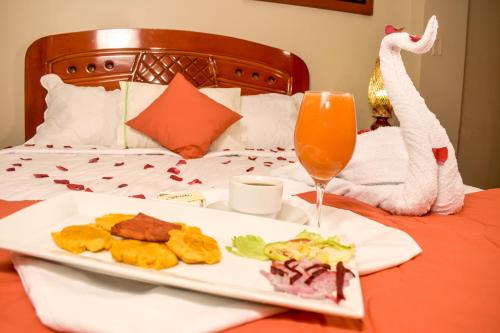 a plate of food and a drink on a bed at Hotel Ventura Isabel in Iquitos