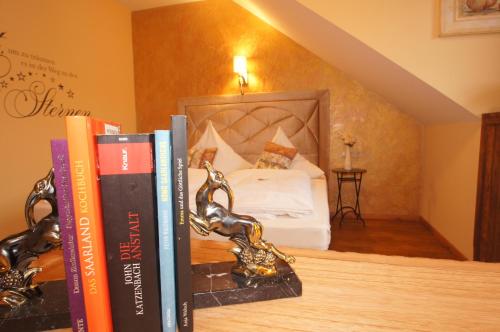 a pile of books on a shelf with a bed at UNO Hotel Chapeau Noir - Free Parking in Überherrn
