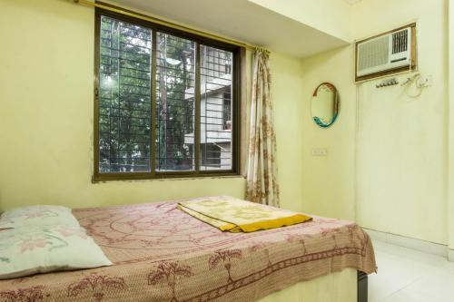 um quarto com uma cama e uma janela em Comfortable Living em Navi Mumbai