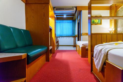a room with two beds and a green chair in it at โรงแรมศิริโฮเต็ล Sirihotel Korat in Nakhon Ratchasima