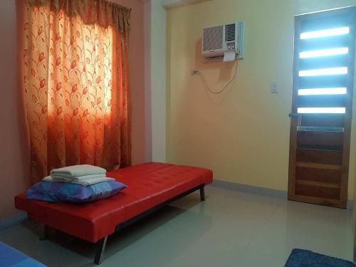 a red bench in a room with a window at Mayon Lodging House in Legazpi