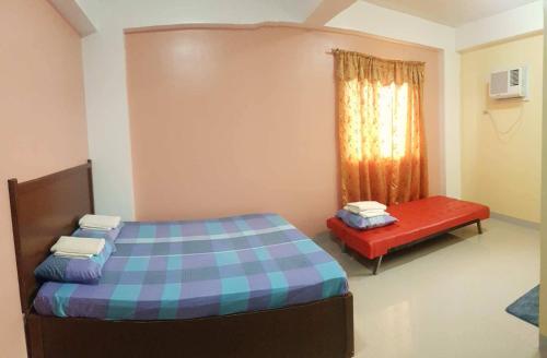 a bedroom with a bed and a red bench at Mayon Lodging House in Legazpi